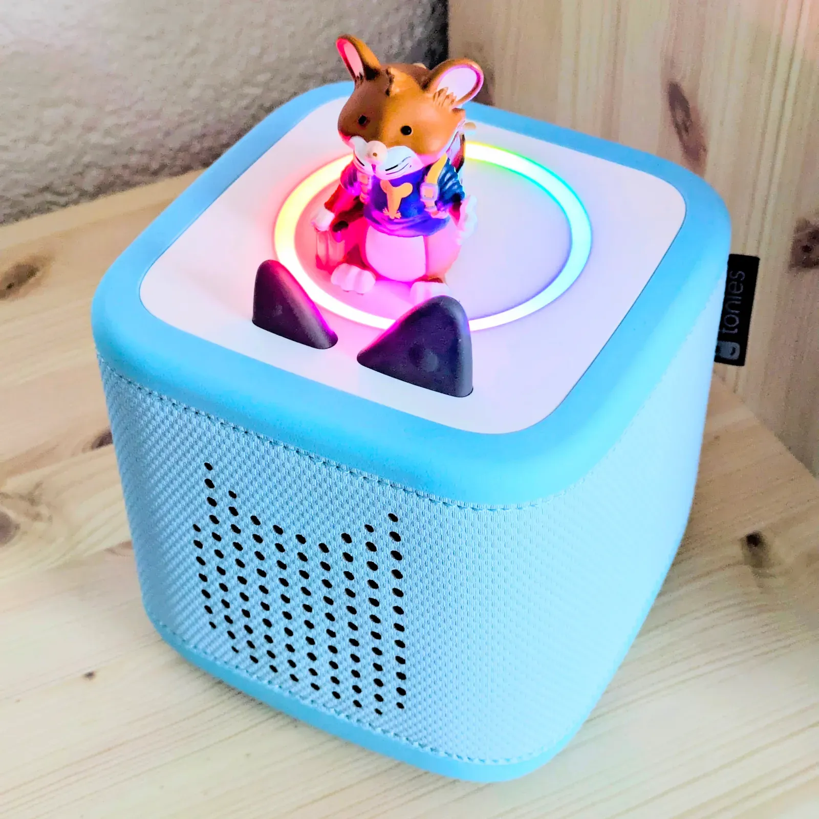 A blue Toniebox 2 with its light ring glowing and a Tonies figure on top